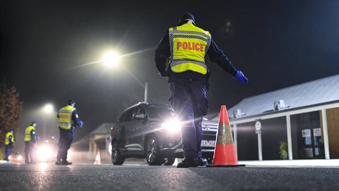 NSW Police officers speak to drivers crossing the border between NSW and Victoria in the NSW-Victoria border town of Albury, NSW.